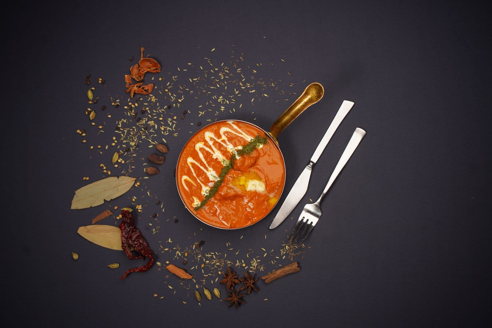 Butter chicken simmering in a dark bowl