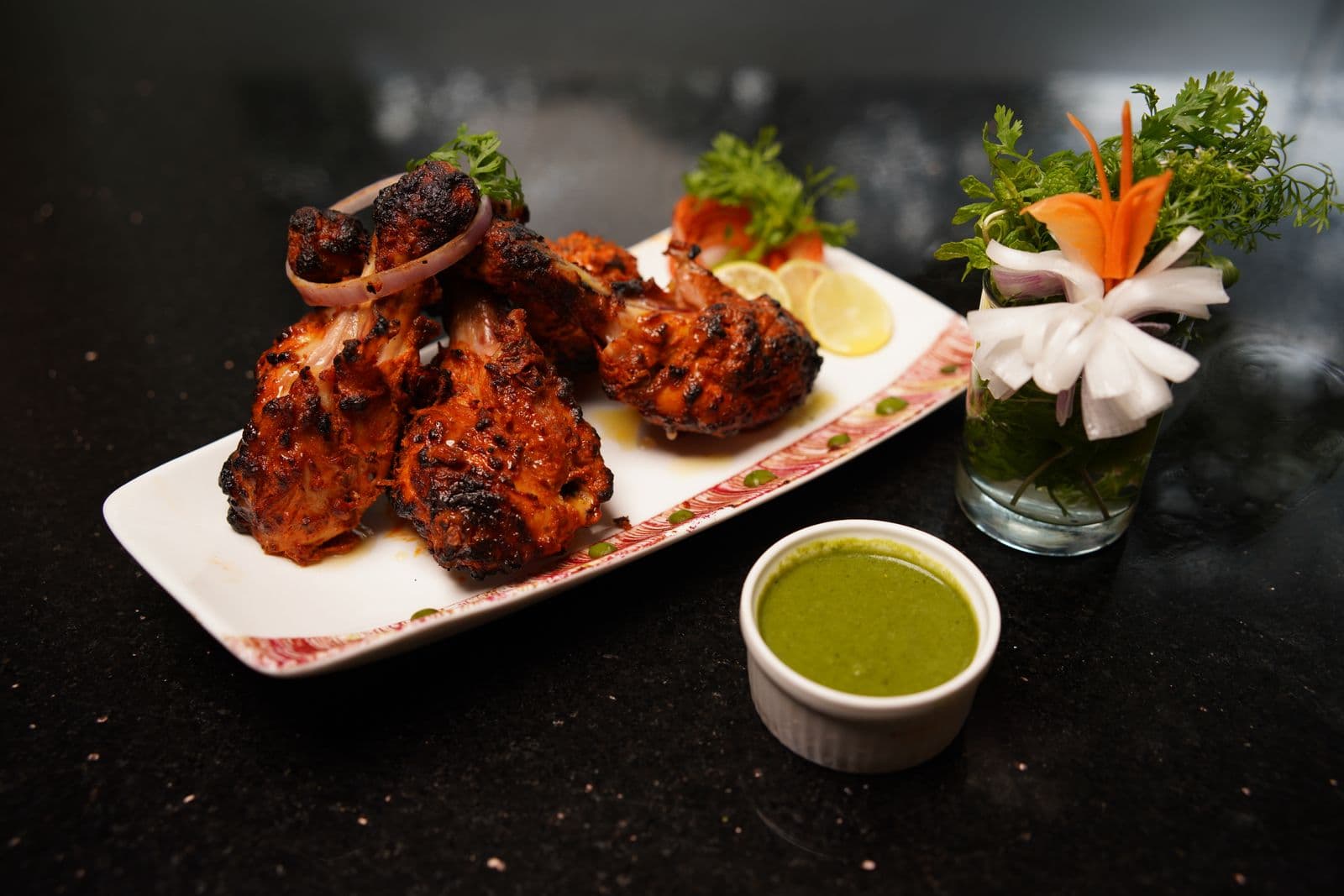 Charred tandoori chicken on a black plate